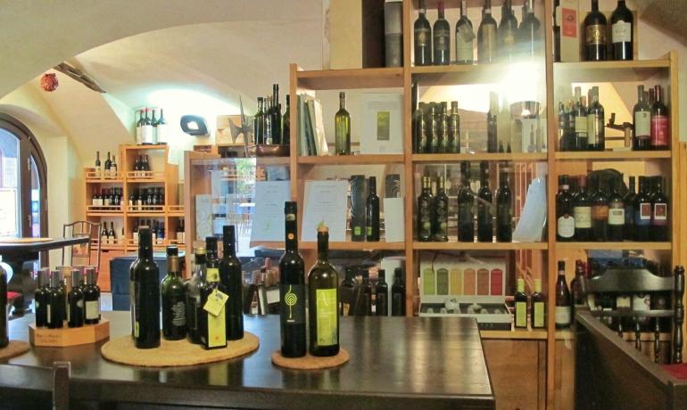 Enoteca con scaffali di vini e oli esposti.