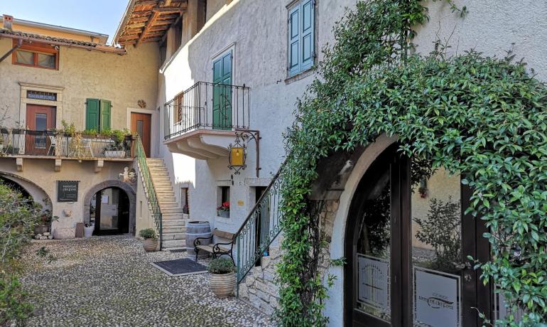 Cortile rustico con piante rampicanti e scale esterne.