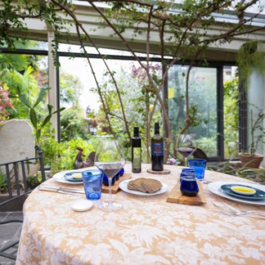 Tavola apparecchiata in giardino con vino, pane e olio d'oliva.