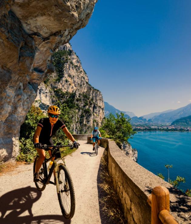 Ciclisti su un sentiero panoramico in montagna con vista sul lago.